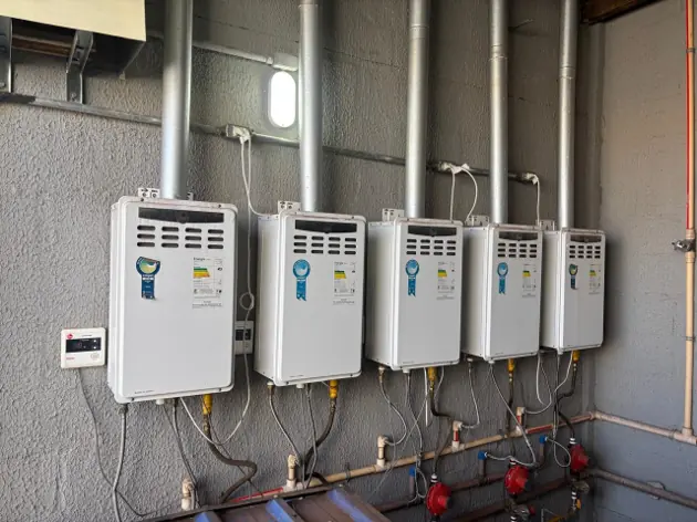 Bateria de aquecedores a gás instalados na parede com tubulação de cobre