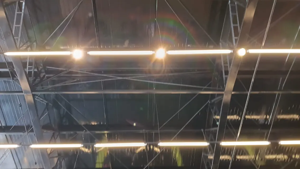 Luminárias lineares acesas na estrutura metálica do teto de uma academia