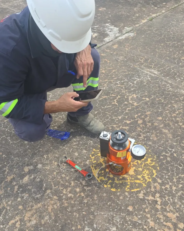 Técnico de capacete realizando teste de arrancamento com equipamento hidráulico