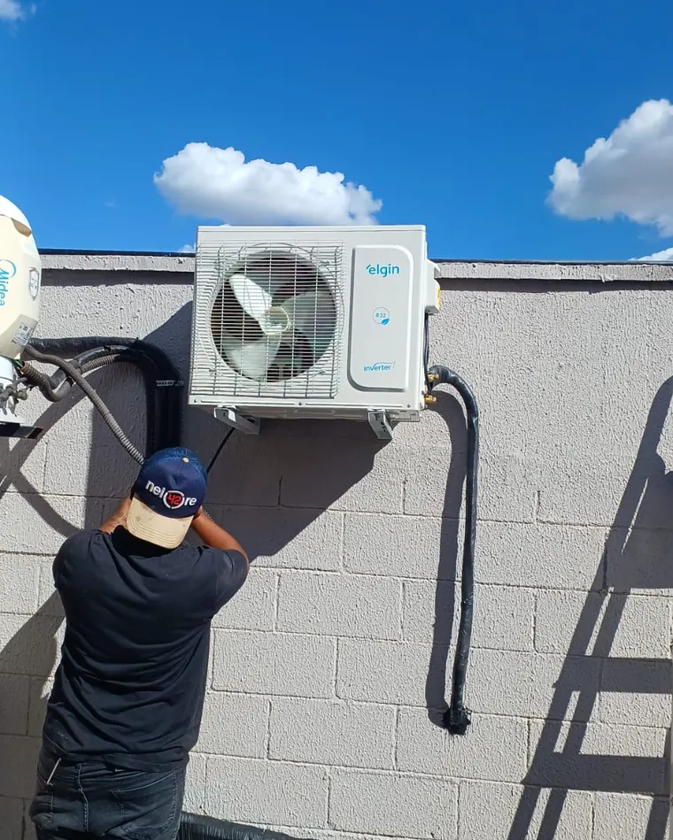 Técnico instalando unidade externa de ar-condicionado na fachada de uma unidade
